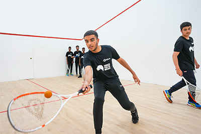 Teenagers playing on a squash court